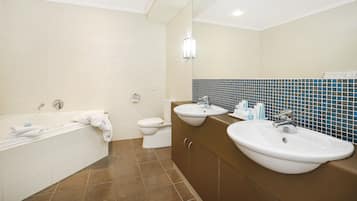Et moderne badeværelse med badekar, to håndvaske og et toilet.