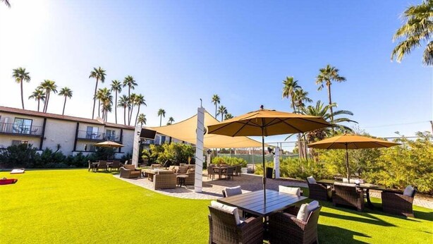 A patio area with outdoor furniture, a pool, and palm trees.