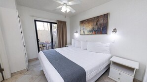 A hotel room with a large bed, a ceiling fan, a painting on the wall, and a sliding glass door leading to a balcony. - 101 - Exclusive Scottsdale Suite | Snowbird Favorite! Gated Resort w/ Heated Pool (Scottsdale)