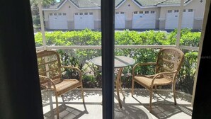 Een balkon met rieten meubels en uitzicht op woongebouwen.