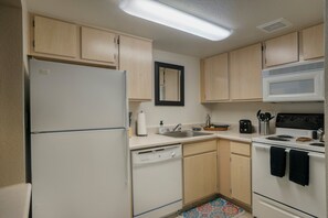 A compact kitchen with a refrigerator, microwave, stove, sink, and wooden cabinets. - 124Bike, Hike, Explore – Adventure-Ready 1BR in Gated Community! (Scottsdale)