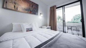 A hotel room with a large bed, a painting on the wall, a nightstand, and a view of the outdoors through a sliding door. - 142 Fully Furnished 1BR Suite-Pet Friendly! (Scottsdale)