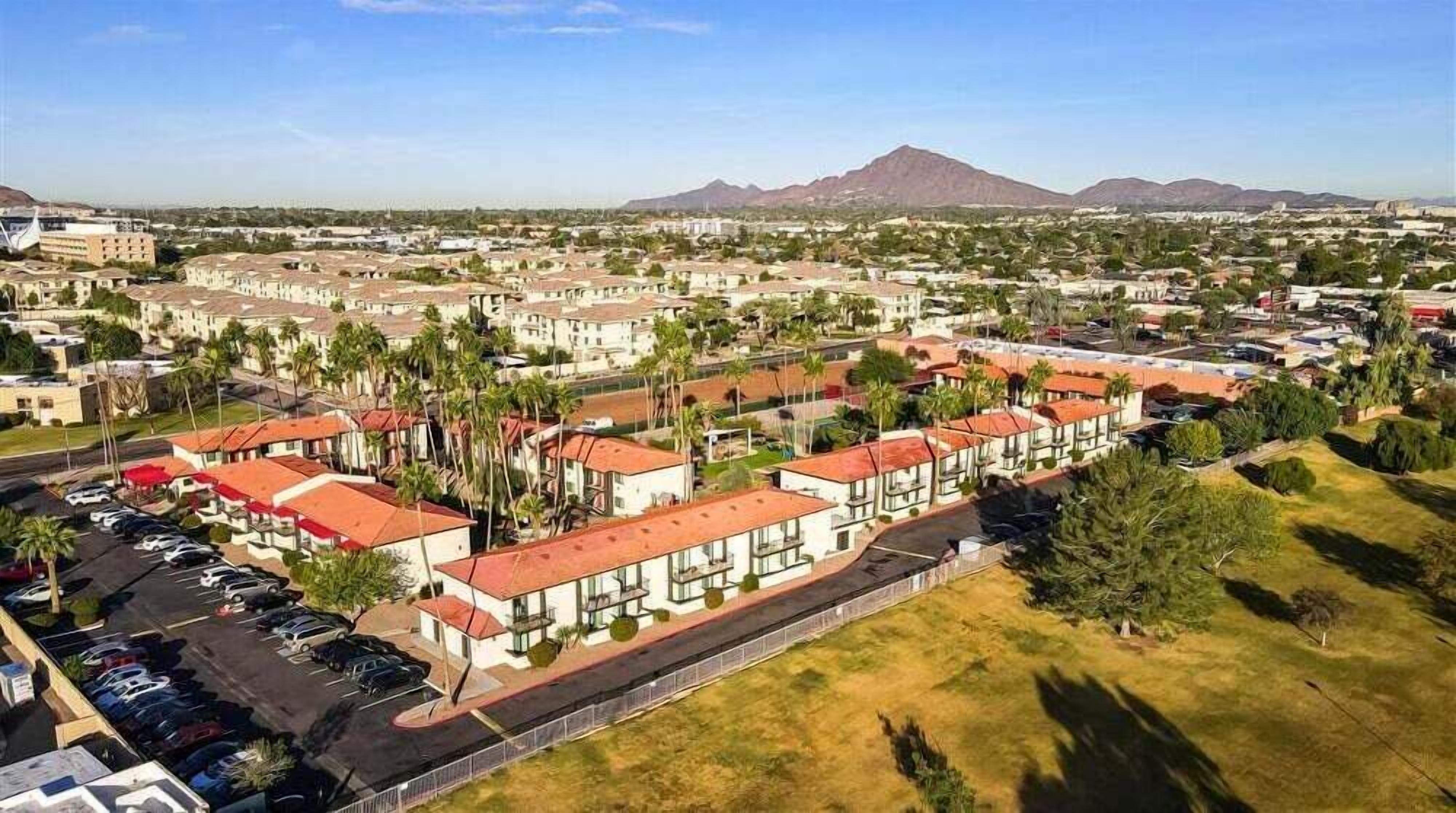 A residential area with multiple-story buildings, a parking lot, and a mountain in the background.