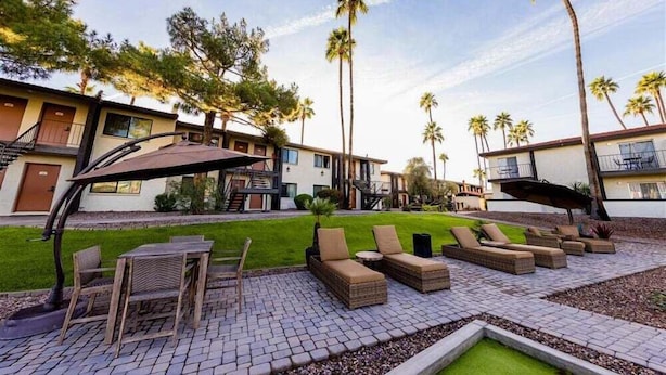 A courtyard with outdoor seating, palm trees, and a building with a modern design. - 142 Fully Furnished 1BR Suite-Pet Friendly! (Scottsdale)