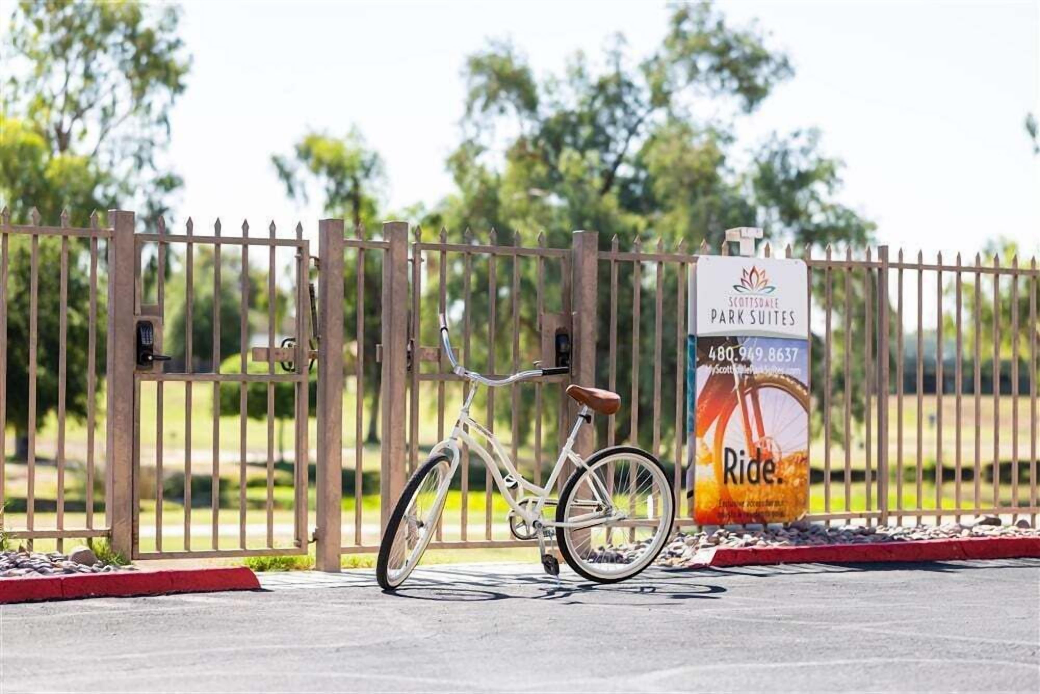 Una bicicletta parcheggiata di fronte a un'area recintata con un cartello per Scottsdale Park Suites.