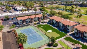 Un hotel con varias edificaciones, cancha de tenis y campo de golf.