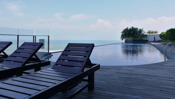Un área junto a la piscina con sillones de descanso y vistas al océano.