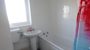 A bathroom with a white sink, a window, and a bathtub. - Huku Kwetu - Brentwood Townhouse (Dunstable)