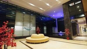 Un hall d’hôtel moderne avec un comptoir d’accueil, un élément décoratif aquatique et des plantes ornementales.