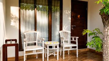 A room with a wooden floor, two white chairs, a small round table, and a door.