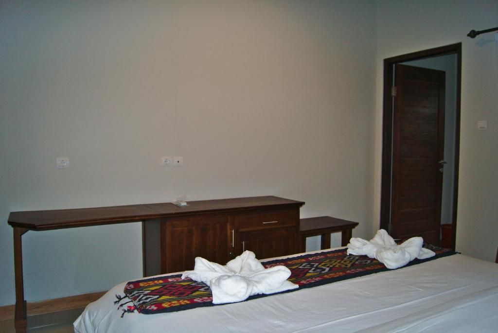 Un dormitorio con una cama, una mesita de noche de madera, un espejo y una puerta.