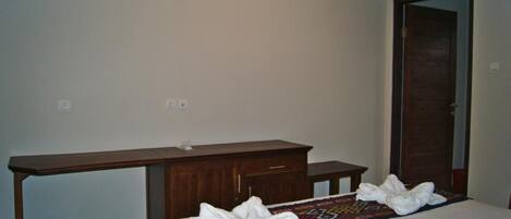 Un dormitorio con una cama, una mesita de noche de madera, un espejo y una puerta.
