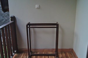 A corner of a room with a wooden floor, a dark-colored metal frame structure, and a white wall-mounted switch.