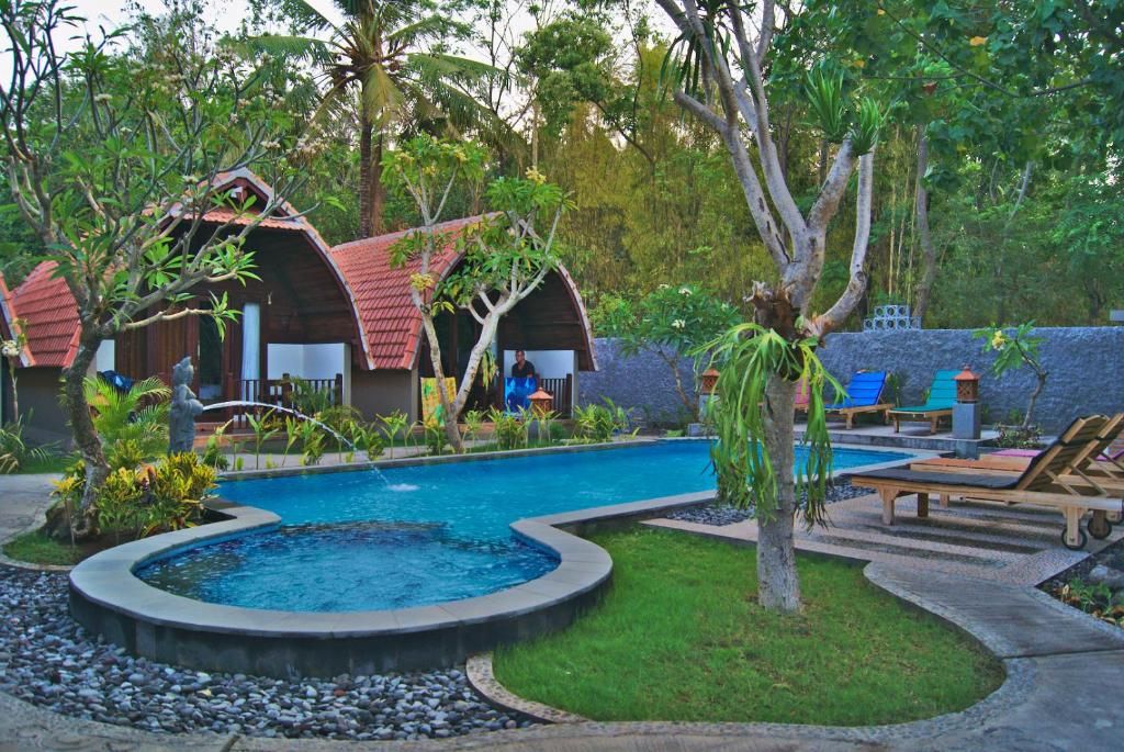 Un resort con varias cabañas, piscina y sillones de descanso.