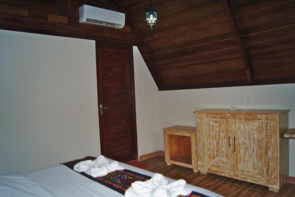 A room with a bed, a wooden cabinet, a door, and a ceiling fan.