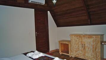 A room with a bed, a wooden cabinet, a door, and a ceiling fan.
