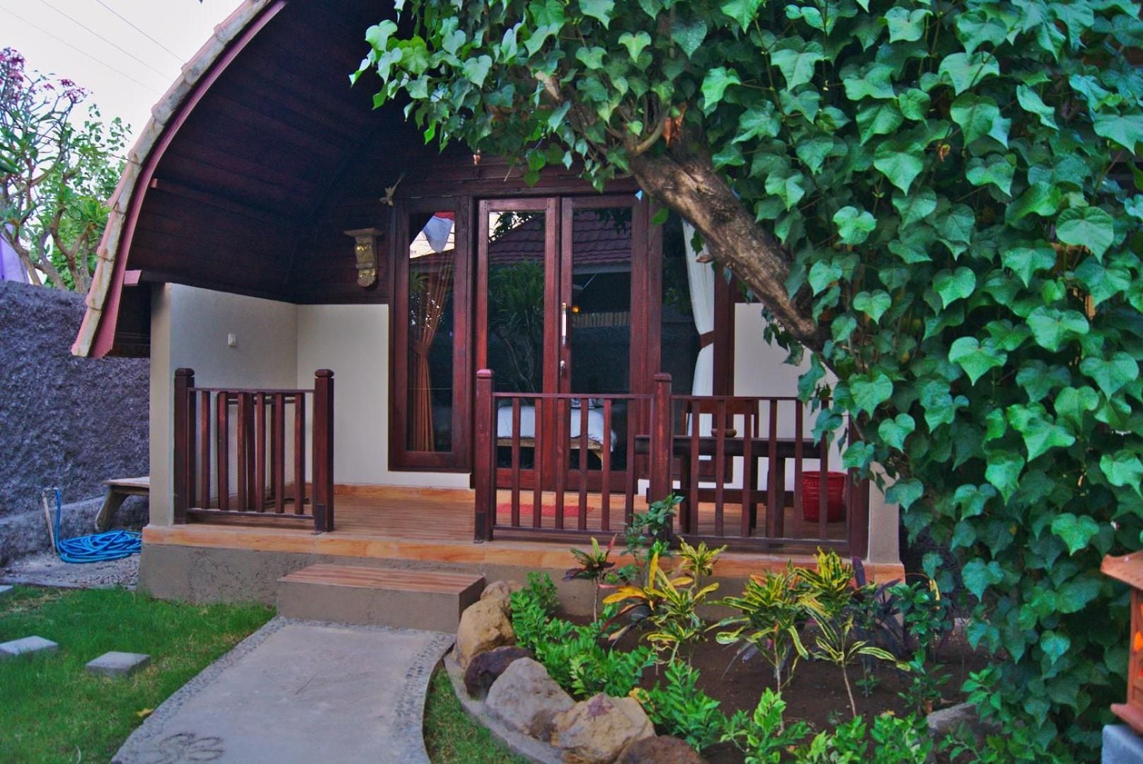 A covered outdoor area with a wooden fence, a stone wall, and a variety of plants.