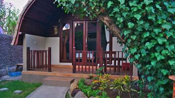 A covered outdoor area with a wooden fence, a stone wall, and a variety of plants.