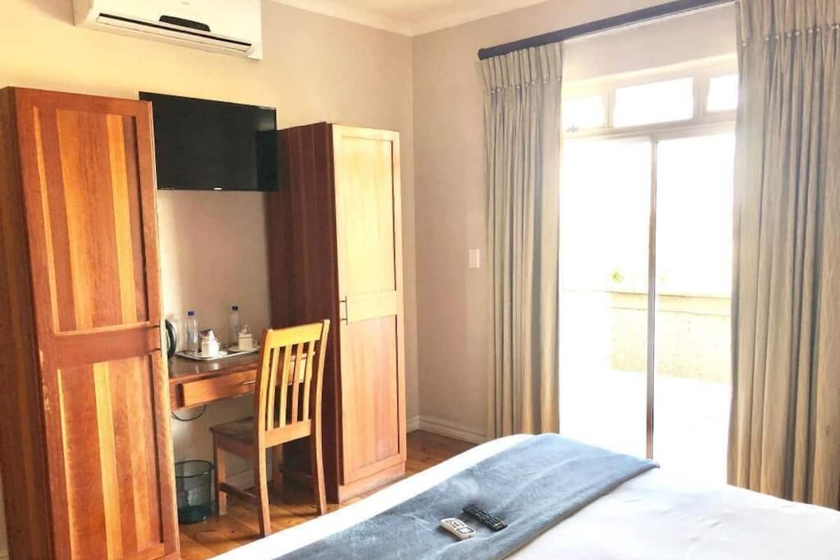 Ein Schlafzimmer mit Bett, Schreibtisch, Stuhl und einem Fenster mit Vorhängen.