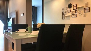 Un espace repas moderne avec une table en verre, des chaises noires et un mur décoré de tableaux encadrés.
