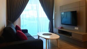 Un salon moderne avec un canapé, une table basse et un téléviseur à écran plat fixé au mur.