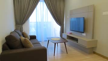 Una sala de estar con un sofá, una mesa de centro y un televisor montado en la pared.