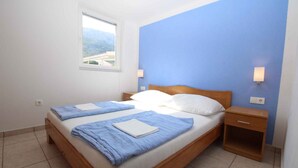 Ein Doppelbett mit hölzernem Kopfteil, zwei Nachttische und ein Fenster mit Bergblick.
