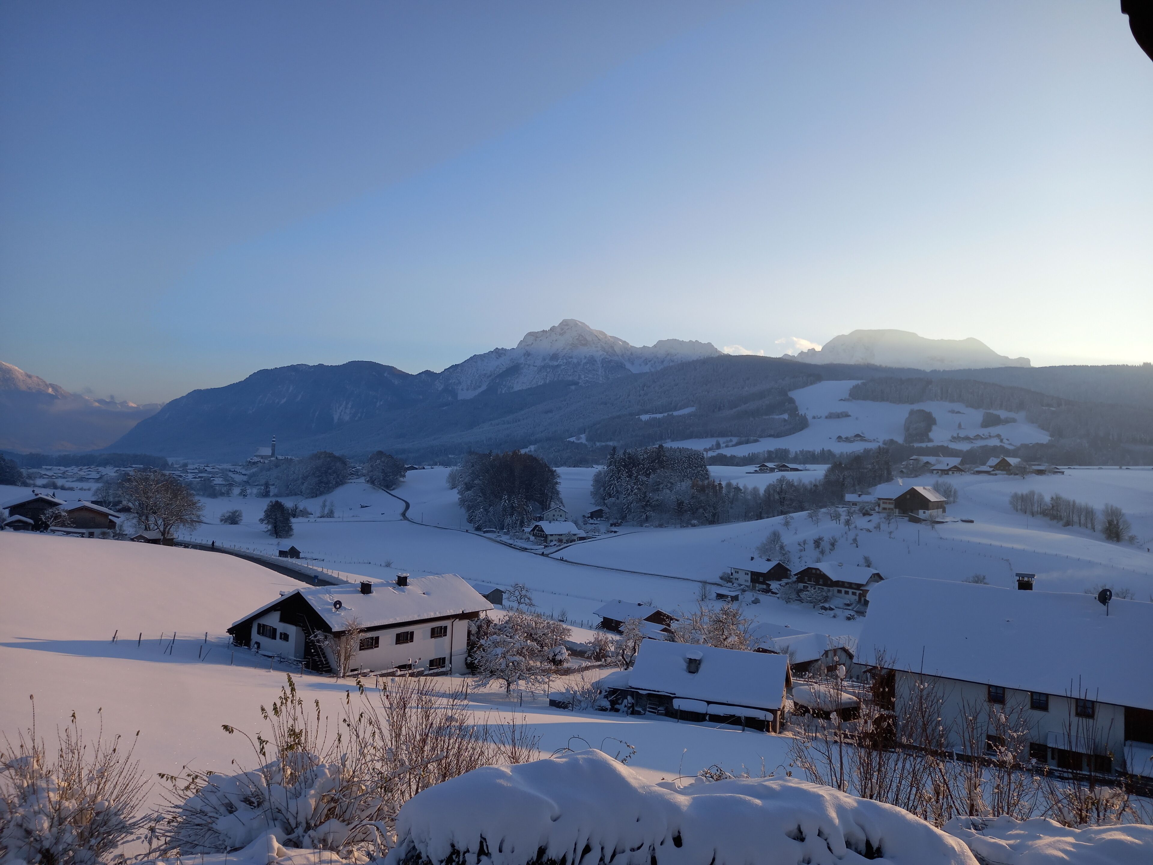 A snow-covered landscape with houses and mountains in the background.
