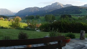 Un banc placé face à un paysage pittoresque d’une vallée, avec des montagnes en arrière-plan.