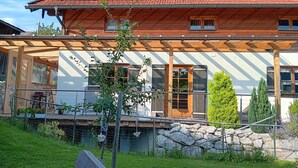 Un chalet en bois doté d’un toit à pente, de grandes fenêtres et de fondations en pierres.