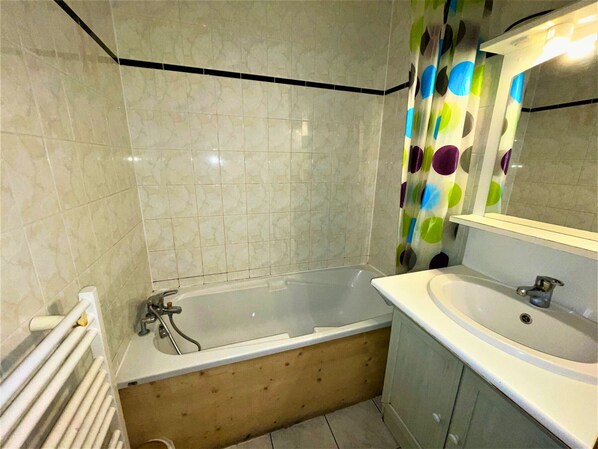Un baño con bañera, lavamanos y espejo.