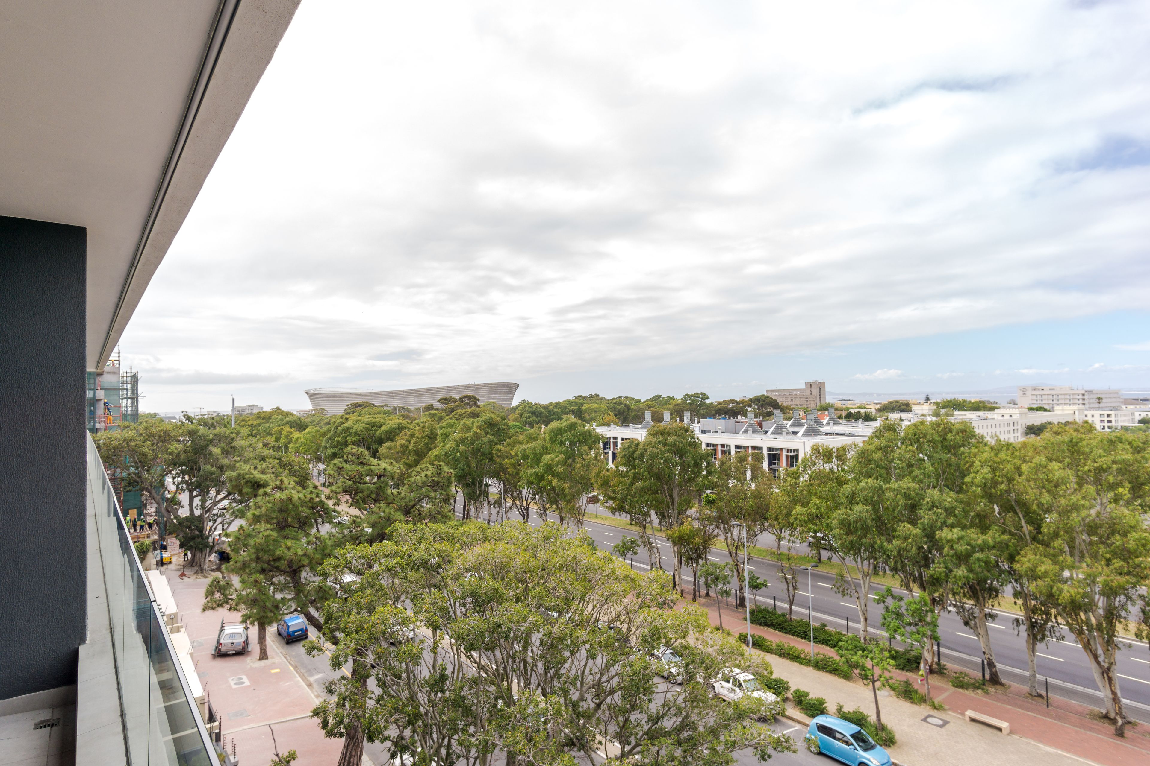 A view from a high-rise building overlooking a cityscape with trees, roads, and buildings.