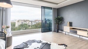 Ein modernes Wohnzimmer mit großem Fenster, Holzboden, einer Couch, einer Lampe und einer Pflanze.