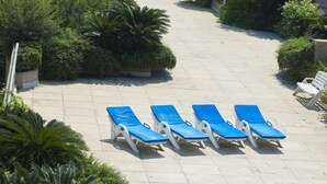 Un espace extérieur carrelé, avec des chaises longues bleues disposées en rangées.