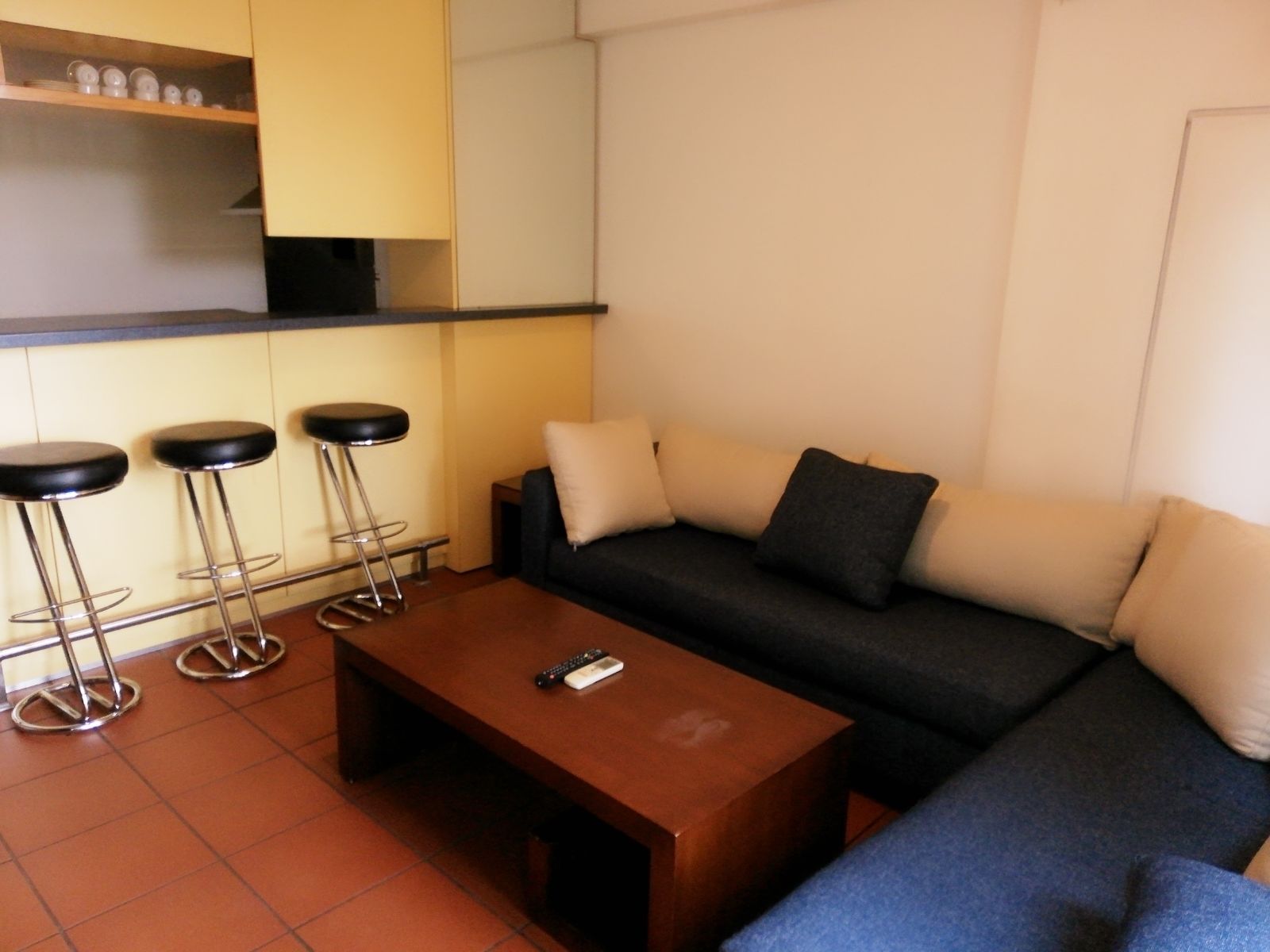 A living area with a sofa, a coffee table, and three bar stools.