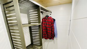 Un letto a castello con struttura in metallo e un piccolo ripiano, una parete rivestita di piastrelle bianche e un soffitto in legno.