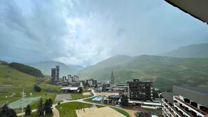 A view of a modern building complex with multiple structures, a sports field, and surrounding green hills. - Economical studio for 4 with south-facing balcony in Les Menuires, pets allowed (Les Menuires)