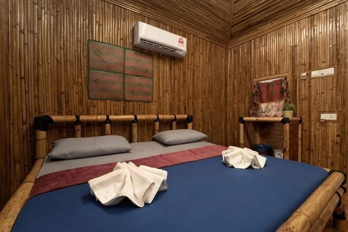 A room with a bed, a wall-mounted air conditioner, and a small shelf with a plant.