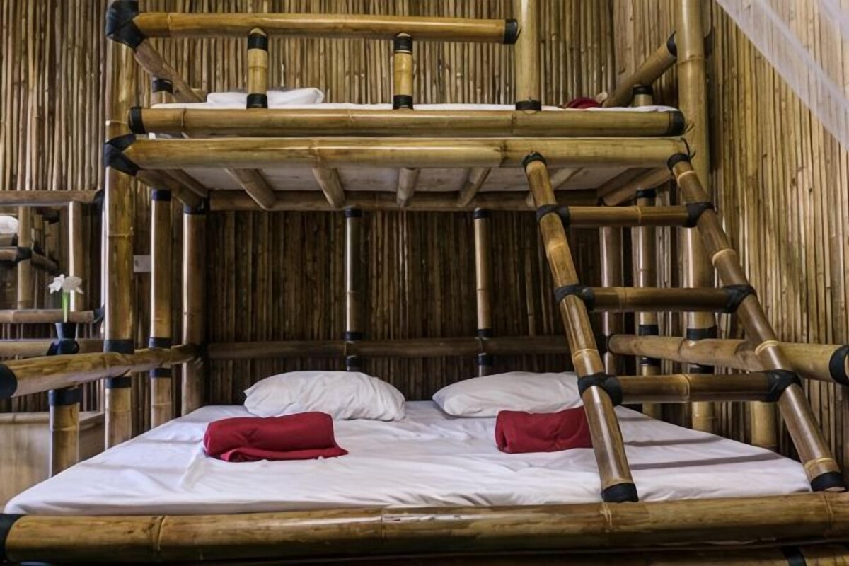 A bunk bed with a bamboo structure, white bedding, and red towels.