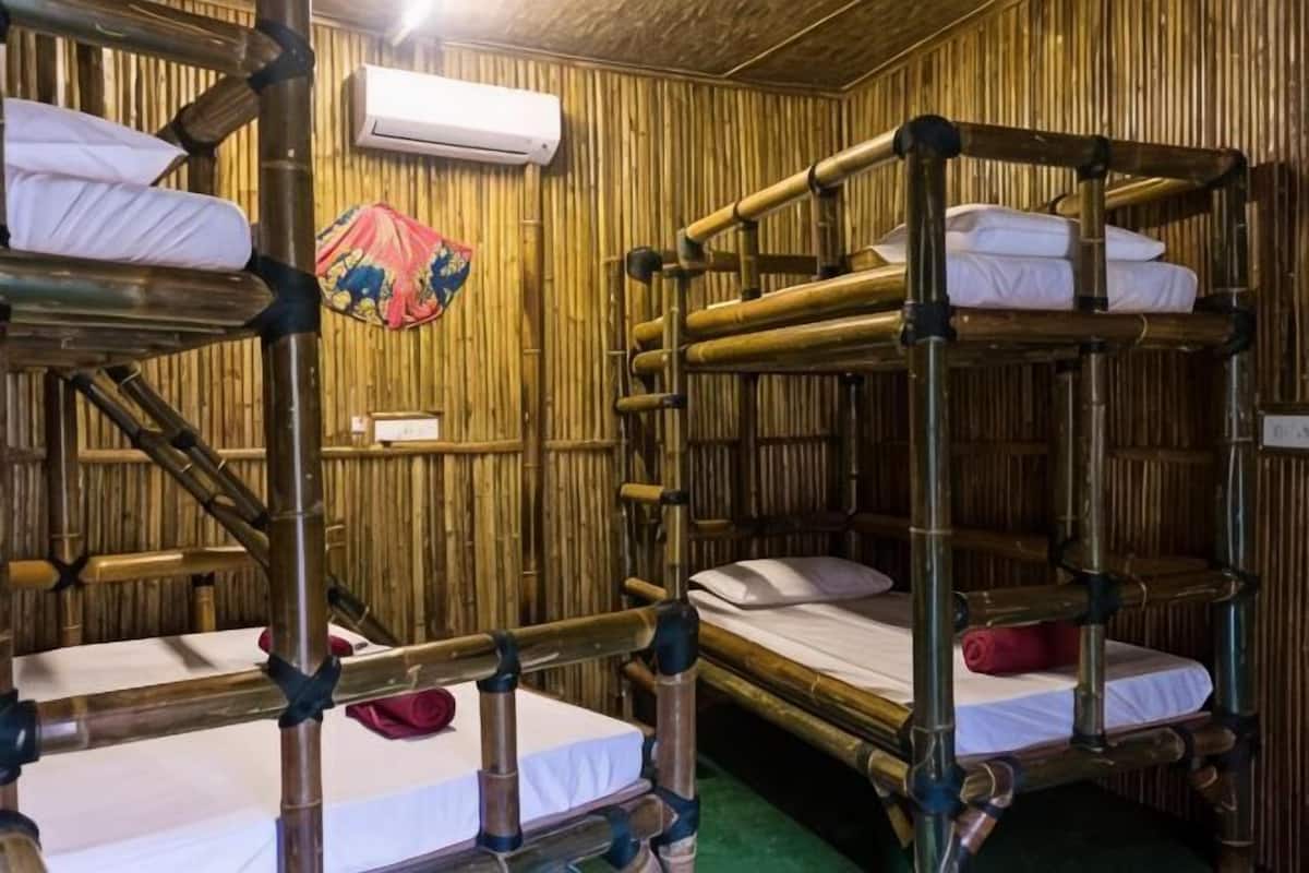 A room with bunk beds, an air conditioning unit, and a decorative item on the wall.