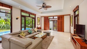 A spacious living room with a large L-shaped beige sofa, a coffee table, and a flat-screen TV on a wooden stand.