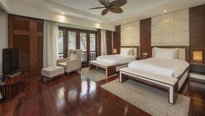 A modern hotel room with a large bed, two bedside tables, a ceiling fan, and a TV.