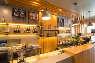 Una zona de bar con detalles de madera, un panel de menú y una máquina de café.