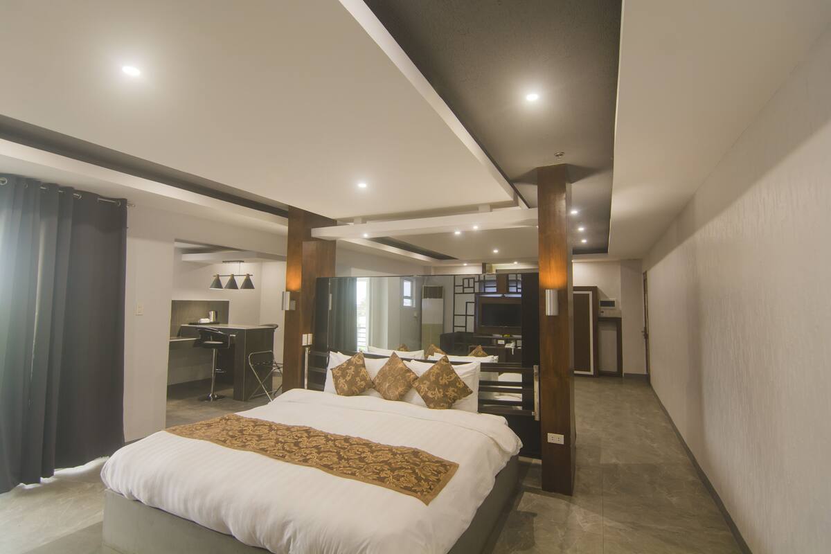 A modern hotel room with a large bed, a desk, and a TV.