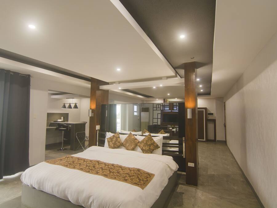 A modern hotel room with a large bed, a desk, and a TV.