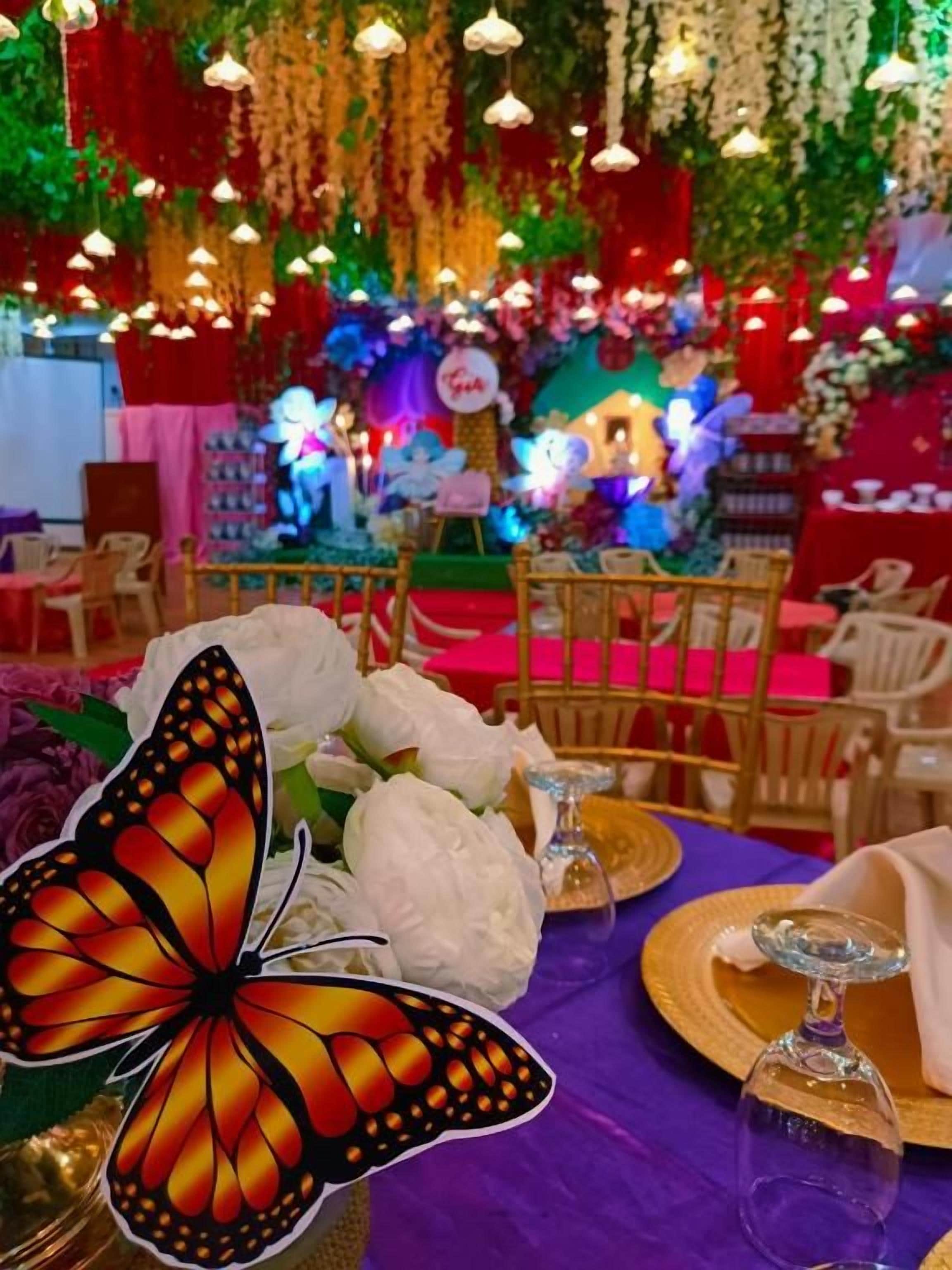 A decorated event space with tables, chairs, and floral arrangements.