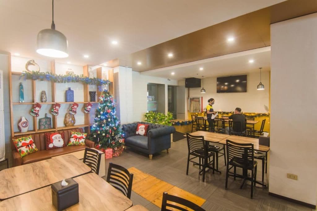 A dining area with a Christmas tree, wooden furniture, and a kitchen in the background.