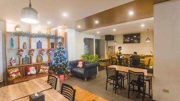 A dining area with a Christmas tree, wooden furniture, and a kitchen in the background.