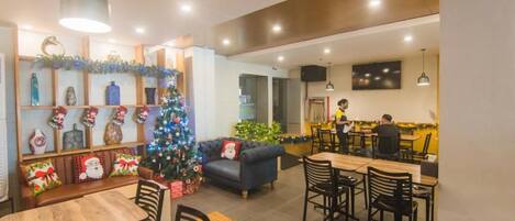 A dining area with a Christmas tree, wooden furniture, and a kitchen in the background.