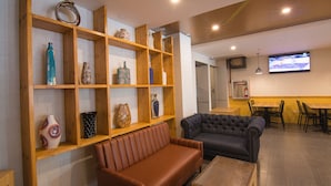 Ein modernes Interieur mit einer braunen Ledersofa, einem dunkelgrauen Sofa, Holzböden mit dekorativen Vasen und einem an der Wand befestigten Fernseher.
